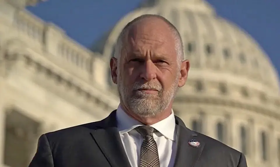 IFA President David Kubal, a balding white man in suit and tie, looks sternly into the camera with the US Capitol dome visible behind him. 