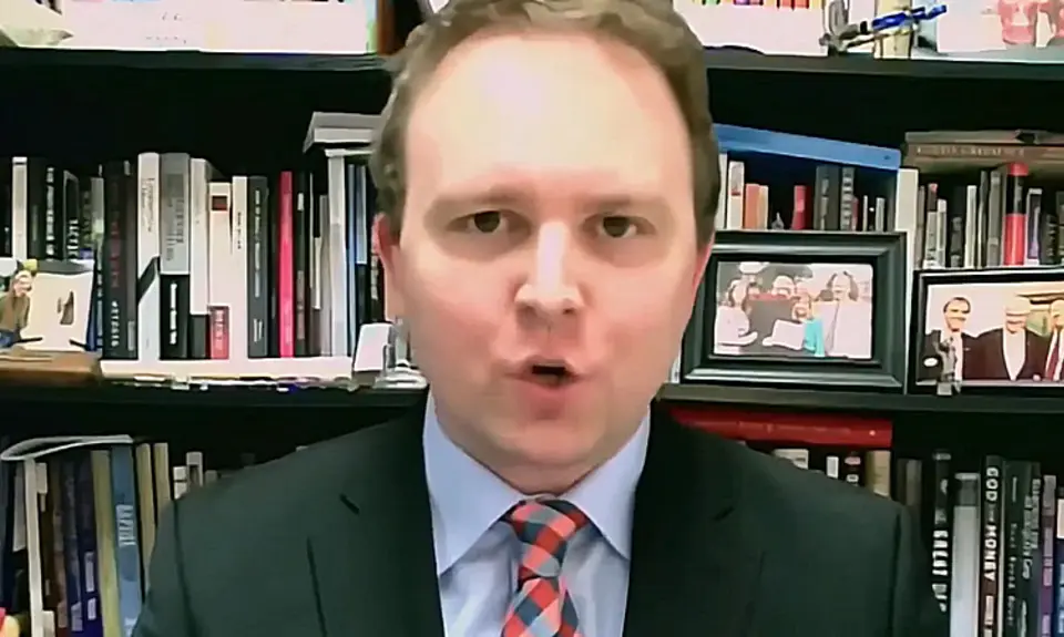 David Closson, a white man with a receding hairline wearing a suit and tie, is seated in front of bookshelves.