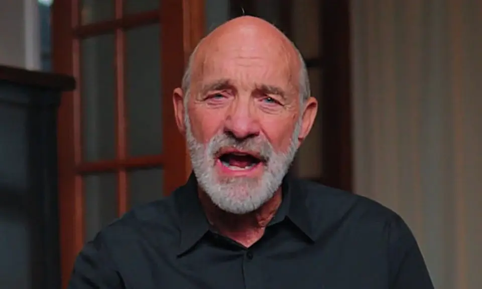 Lou Engle, a bald white man with a gray beard, is seated in what appears to be a home library, speaking directly into the camera.