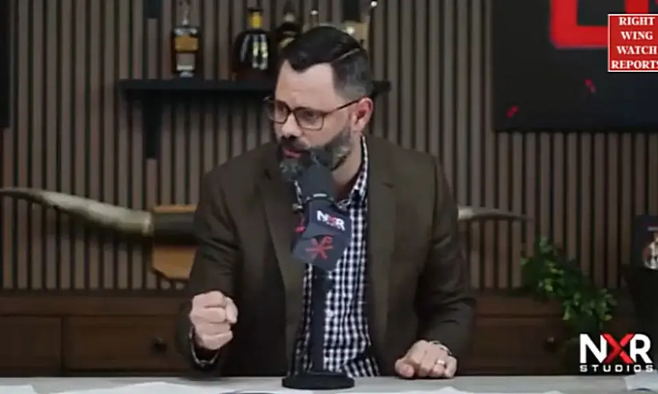 Joel Webbon, seated in his studio, clenches his right fist