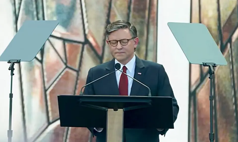 House Speaker Mike Johnson pictured standing at a lectern on the outdoor stage at the Rededicate 250 event.