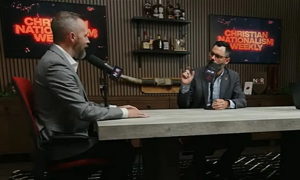 Dale Partridge and Joel Webbon are seated at a table, both with microphones in front of them; screens in the background display the text "Christian Nationalism Weekly"