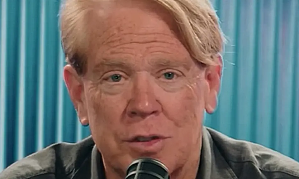 Close-up image of white man with reddish blonde hair speaking into a microphone.