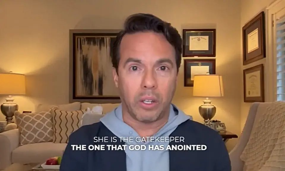 Samuel Rodriguez speaks into a camera in what appears to be a living room setting. In this image from a video, captioned text reads "She is the gatekeeper, the one that God has anointed." 