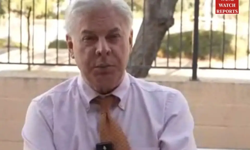 Lance Wallnau seated outdoors in shirt and tie, tree and fence visible behind him
