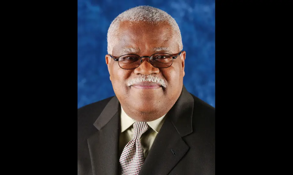 A photo of Reginald Weaver in a dark suit with a blue background
