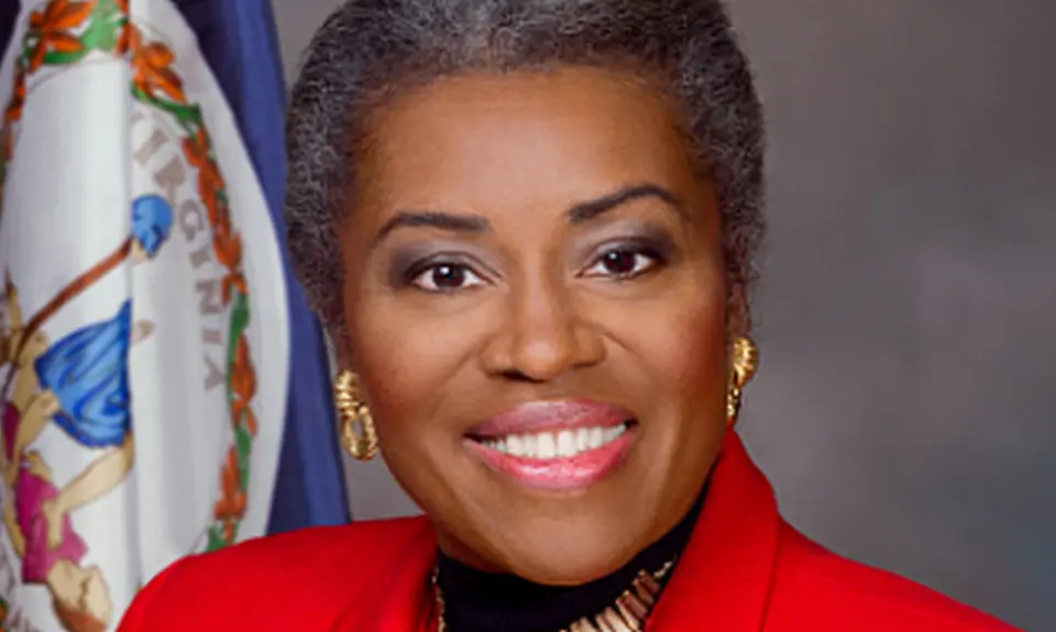 Close crop of official portrait of Virginia Lt. Gov. Winsome Earle-Sears, a black woman wearing a bright red suit jacket, with a Virginia flag visible over her right shoulder. 