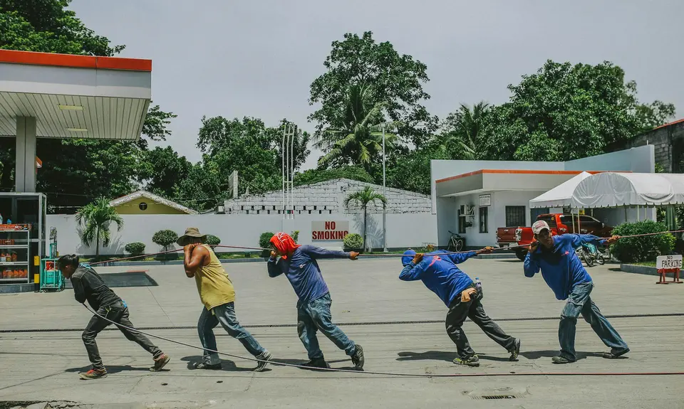 A group of five workers pull a rope