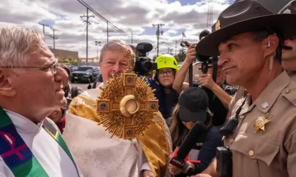 A member of Illinois State Police relays the message to priests that ICE denied them access to detainees to provide them communion, outside a U.S. Immigration and Customs Enforcement facility in Broadview, Ill., Saturday, Oct. 11, 2025. (AP Photo/Adam Gray)