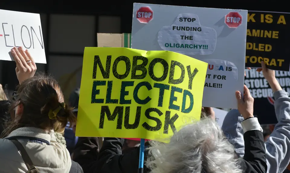 Protestors holding a sign that reads "nobody elected musk"