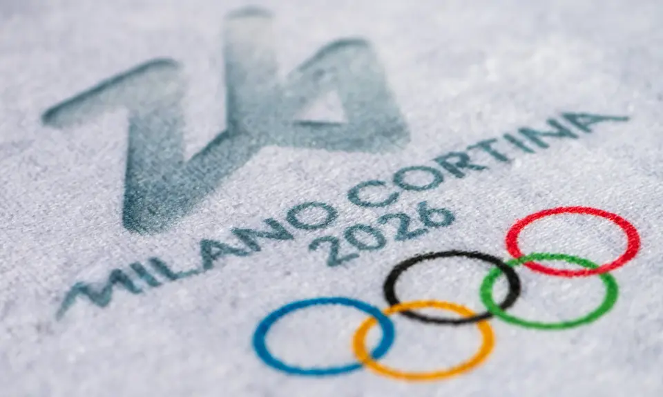 A close up of an ice rink that says "Milan Cortina 2026" and has the olympic logo