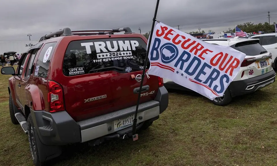 Truck with a Trump window decal and a flag that reads "secure our borders"