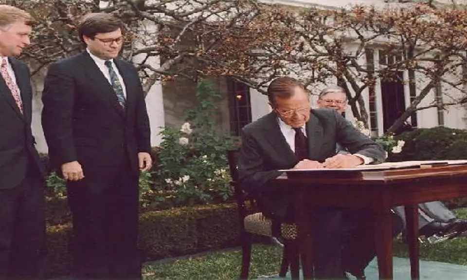 President George H. W. Bush signs the Civil Rights Commission Reauthorization Act in the Rose Garden of the White House. Beside him are Attorney General William Barr and Vice President Dan Quayle. 21 Nov 91