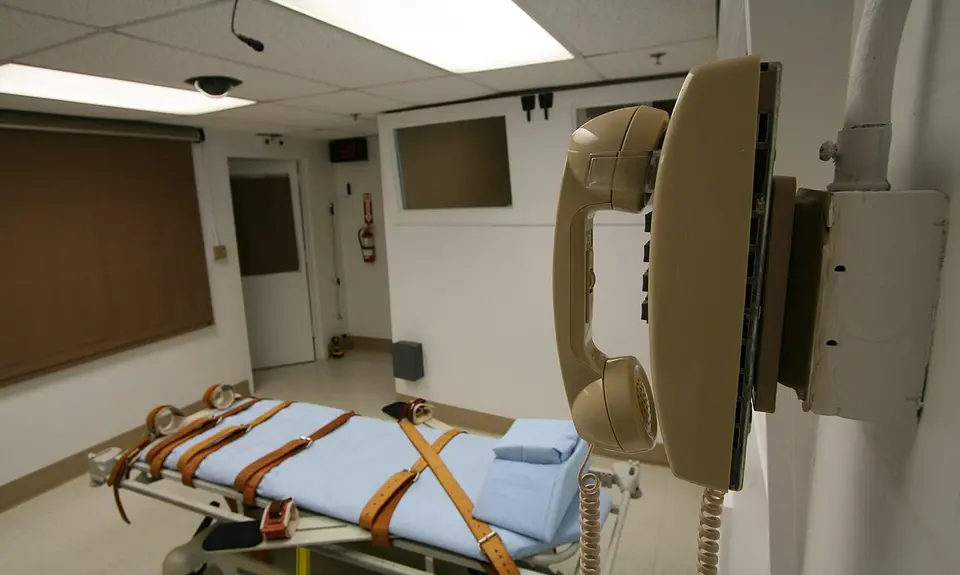 An execution chamber with a telephone and a hospital bed with straps.