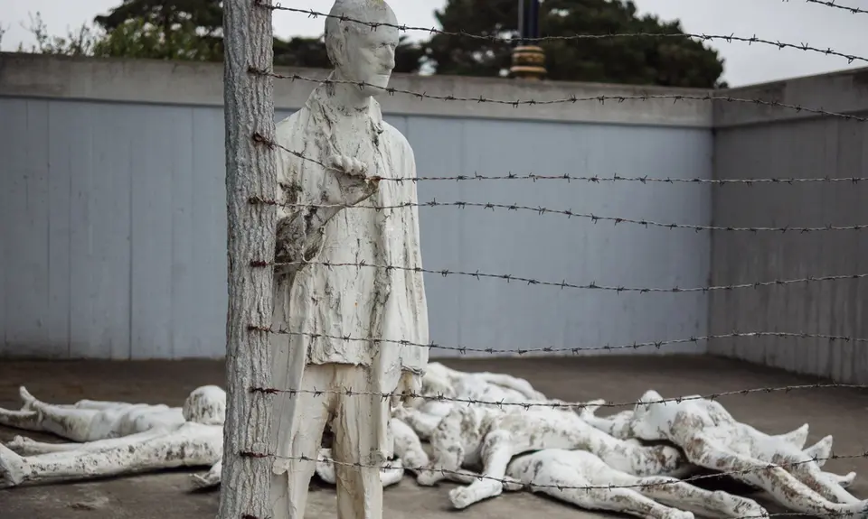 An art instillation depicting bodies laying on the ground and one man holding onto a barbed wire fence at the Holocaust Museum