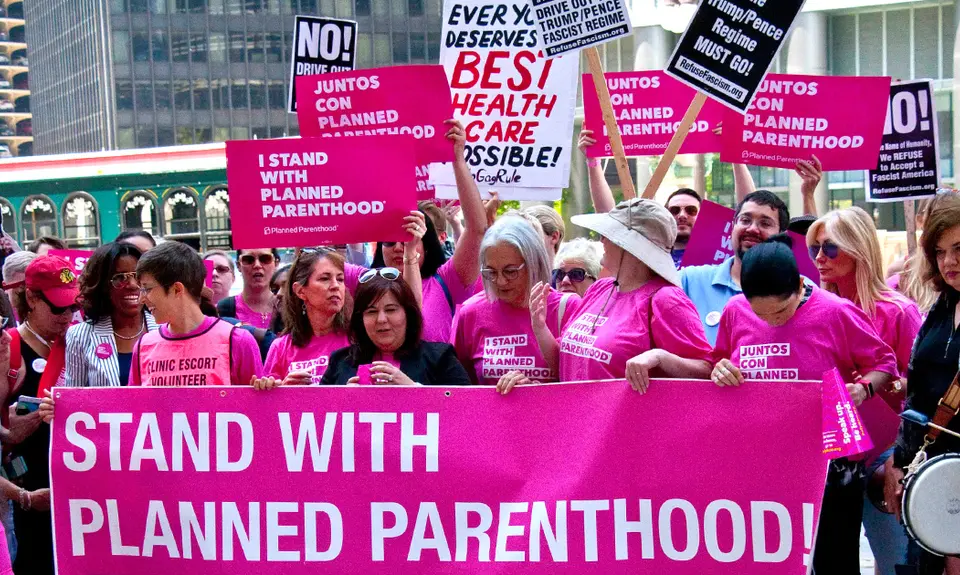 Protesters in Chicago wearing pink and carrying signs that say "I stand with Planned Parenthood."