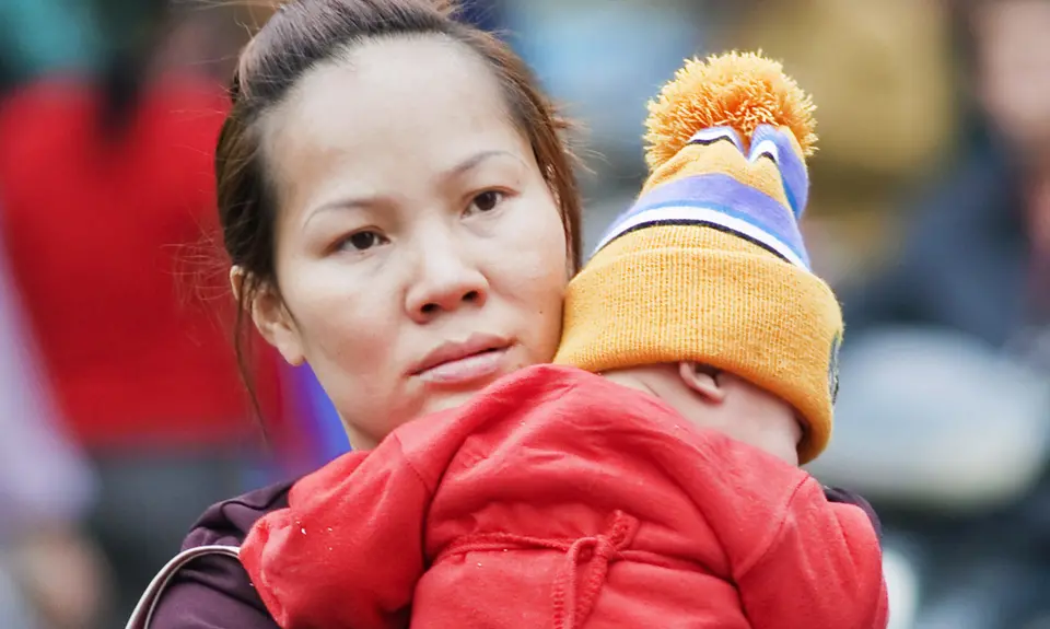 A woman holds her toddler in her arms.