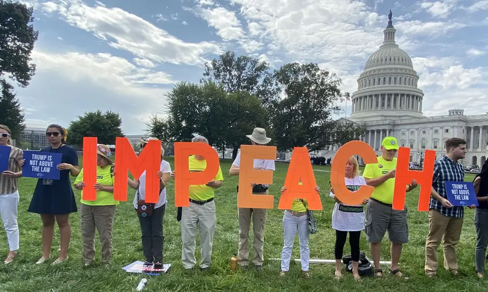 A line of activists in from of the U.S. Capitol Building holding the letters of the word "IMPEACH"