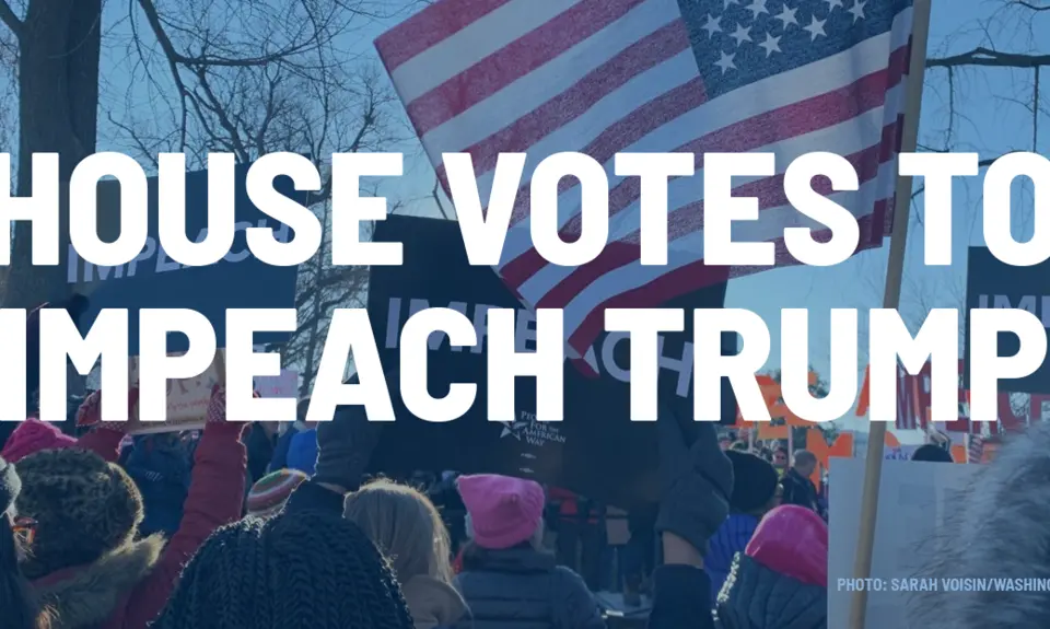 Rally-goers hold signs demanding the impeachment of Trump