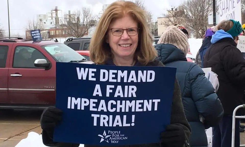 PFAW activist holds a sign outside of Senator Joni Ernst's office in Cedar Rapids