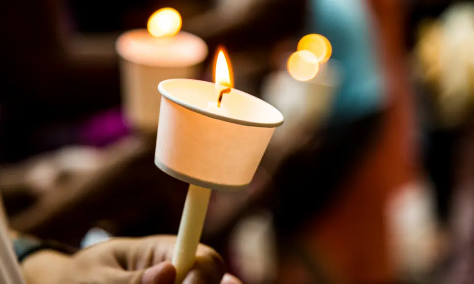 Hands holding candles with paper wax protectors.