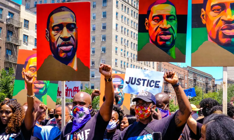 Protesters holding signs featuring George Floyd's image.