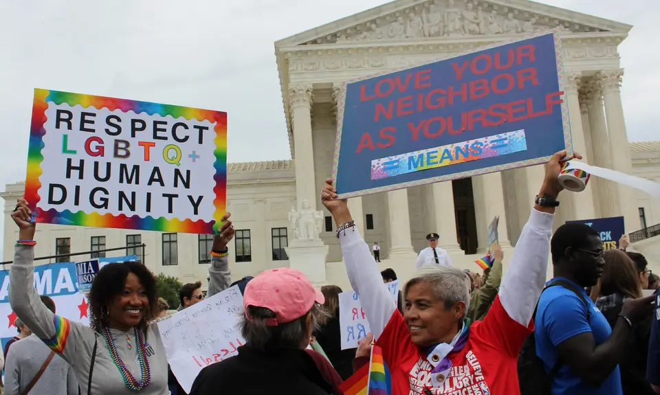 Protestors hold signs supporting LGBTQ rights outside the Supreme Court Building.