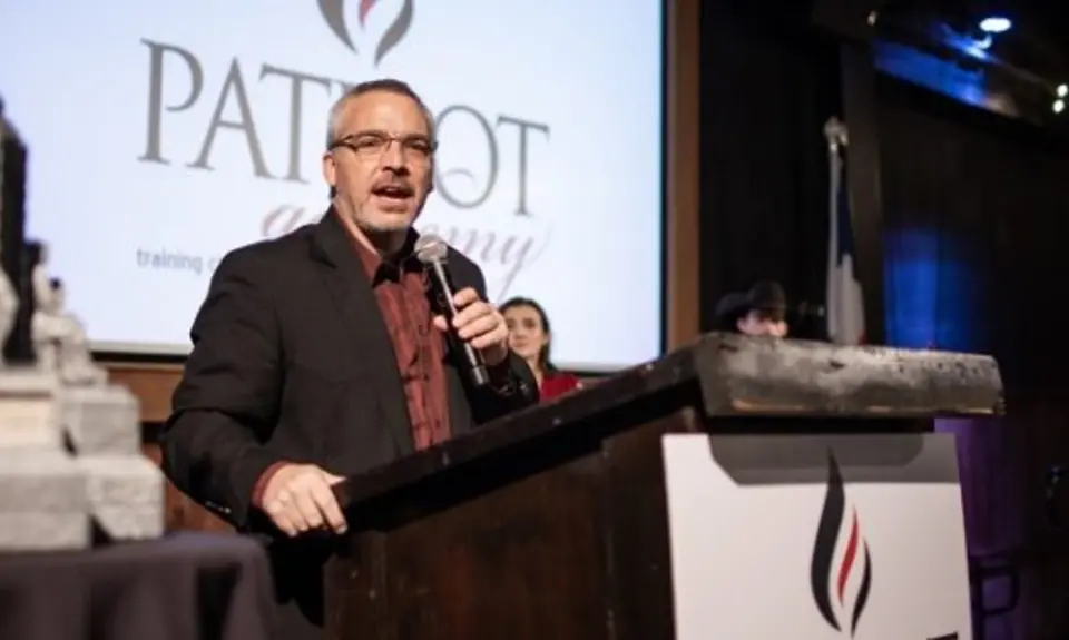 Rick Green standing at a podium and holding a microphone.