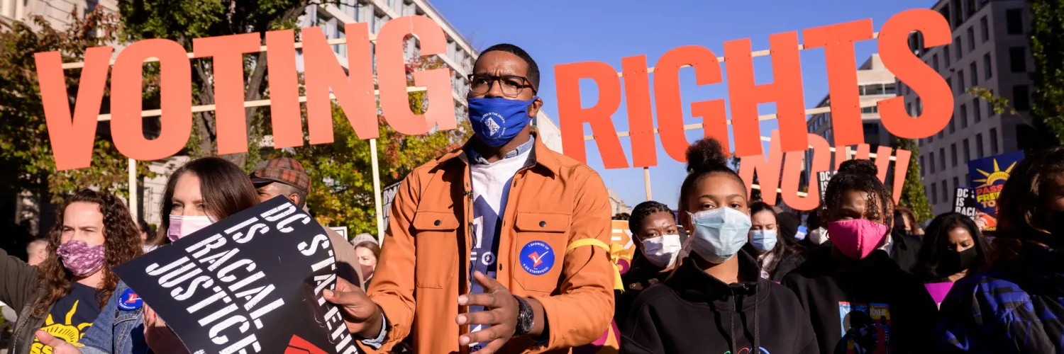 Image of protesters with large letters that say "voting rights" behind them