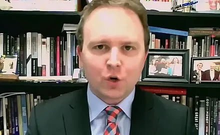 David Closson, a white man with a receding hairline wearing a suit and tie, is seated in front of bookshelves.