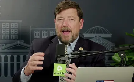 Ed Martin is on the set of his Pro America Report podcast, seated behind his laptop and a microphone bearing the logo of the Rumble video platform.