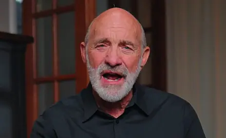 Lou Engle, a bald white man with a gray beard, is seated in what appears to be a home library, speaking directly into the camera.
