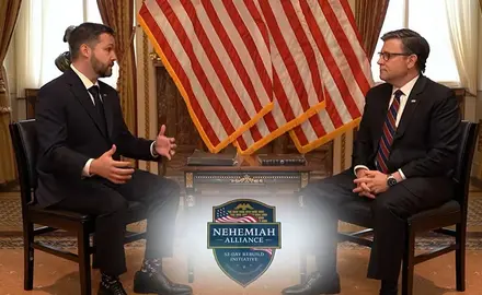 House Speaker Mike Johnson and Pastor Tyler Feller are seated and facing each other in front of several American flags; the shield-shaped logo of the Nehemiah Alliance is superimposed on the screen in the foreground