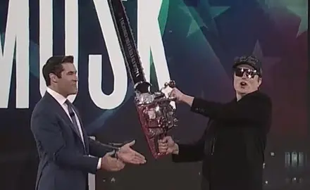 Elon Musk on stage at CPAC brandishing a chain saw. 