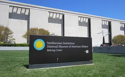 Photo shows exterior of museum with sign out front that says Smithsonian Institution National Museum of American History Behring Center