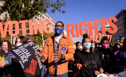 Image of protesters with large letters that say "voting rights" behind them