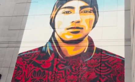 A mural of a young man with text that says "demand change"