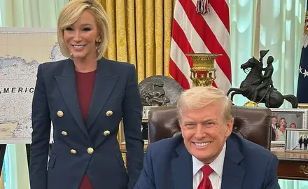 Donald Trump is seated at his desk in the Oval Office, with White standing next to and slightly behind him, both smiling for the camera. Partially visible behind White is a map on an easel touting the "Gulf of America."