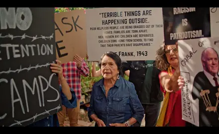 Activist Dolores Huerta surrounded by protestors rallying against ICE