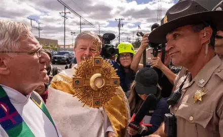 A member of Illinois State Police relays the message to priests that ICE denied them access to detainees to provide them communion, outside a U.S. Immigration and Customs Enforcement facility in Broadview, Ill., Saturday, Oct. 11, 2025. (AP Photo/Adam Gray)