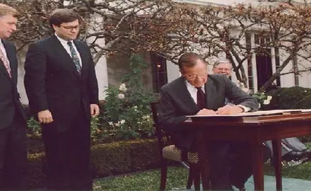 President George H. W. Bush signs the Civil Rights Commission Reauthorization Act in the Rose Garden of the White House. Beside him are Attorney General William Barr and Vice President Dan Quayle. 21 Nov 91
