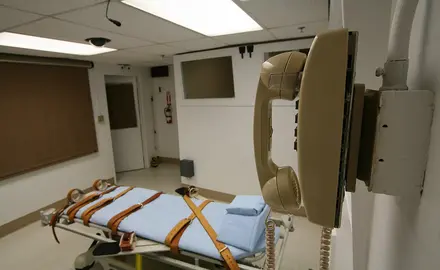 An execution chamber with a telephone and a hospital bed with straps.