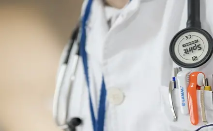 Close up of a doctor's stethoscope and pocket full of pens and pen lights