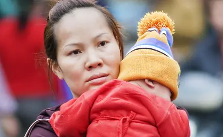 A woman holds her toddler in her arms.