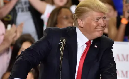 Donald Trump smiles in front of a podium
