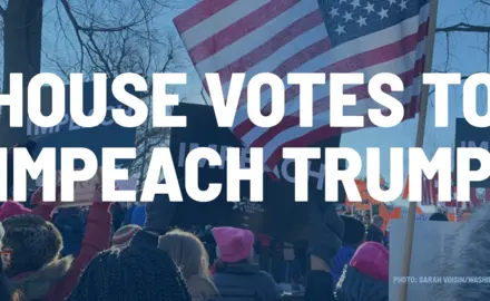 Rally-goers hold signs demanding the impeachment of Trump