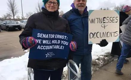 Two PFAW supporters hold signs outside of Sen. Joni Ernst's office in Cedar Rapids