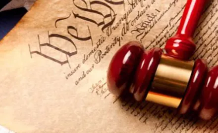 A red gavel lays on top of the Constitution