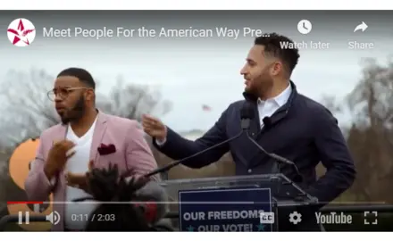 A still of Svante Myrick speaking at a podium with a sign language interpreter next to him.