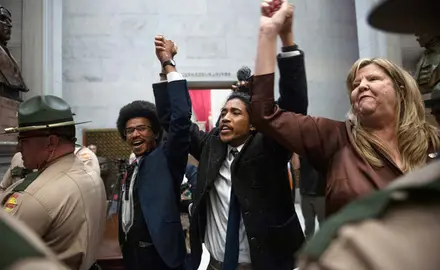 Rep. Justin Pearson, Rep. Justin Jones, Rep. Gloria Johnson People hold their hands up as they exit the House Chamber doors at the Tennessee State Capitol Building